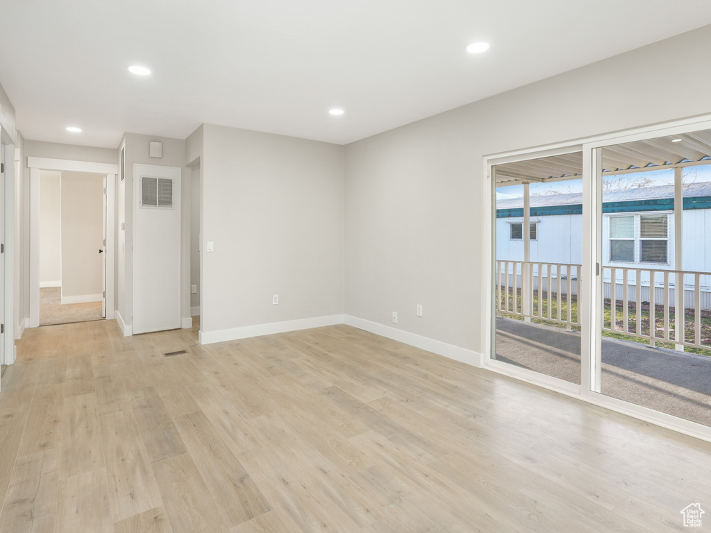 Unfurnished room featuring a skylight and light hardwood / wood-style flooring