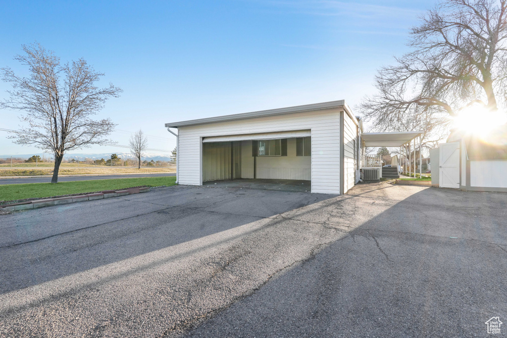 Garage with a lawn, central air condition unit, and a carport