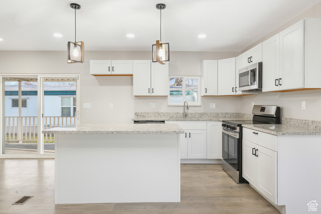 Kitchen featuring white cabinetry, a center island, stainless steel appliances, and pendant lighting