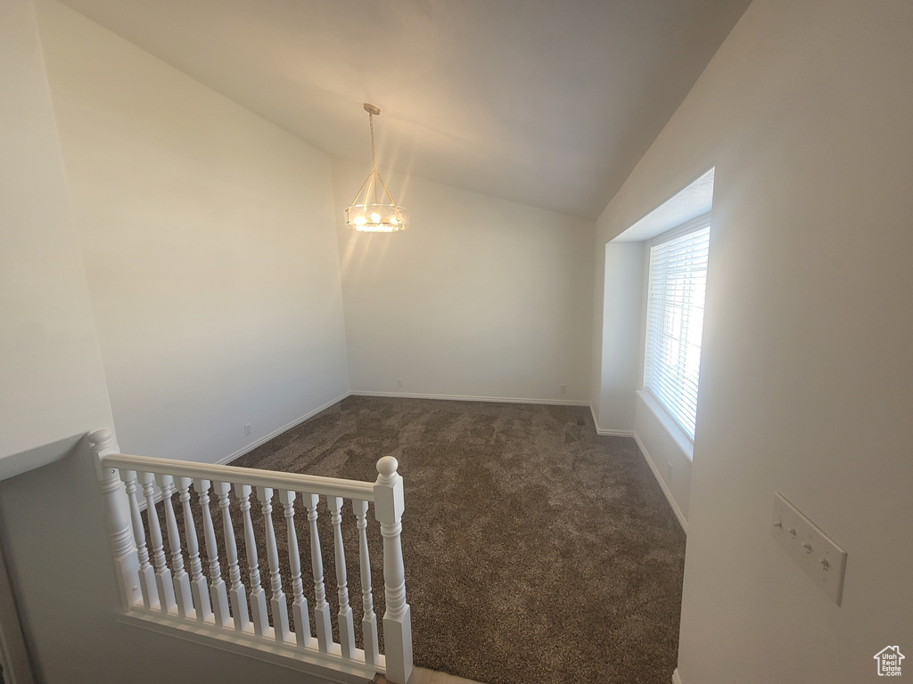 Unfurnished room with dark carpet and lofted ceiling