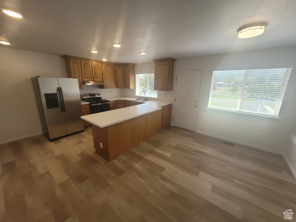 Kitchen with sink, light wood-type flooring, kitchen peninsula, and stainless steel appliances
