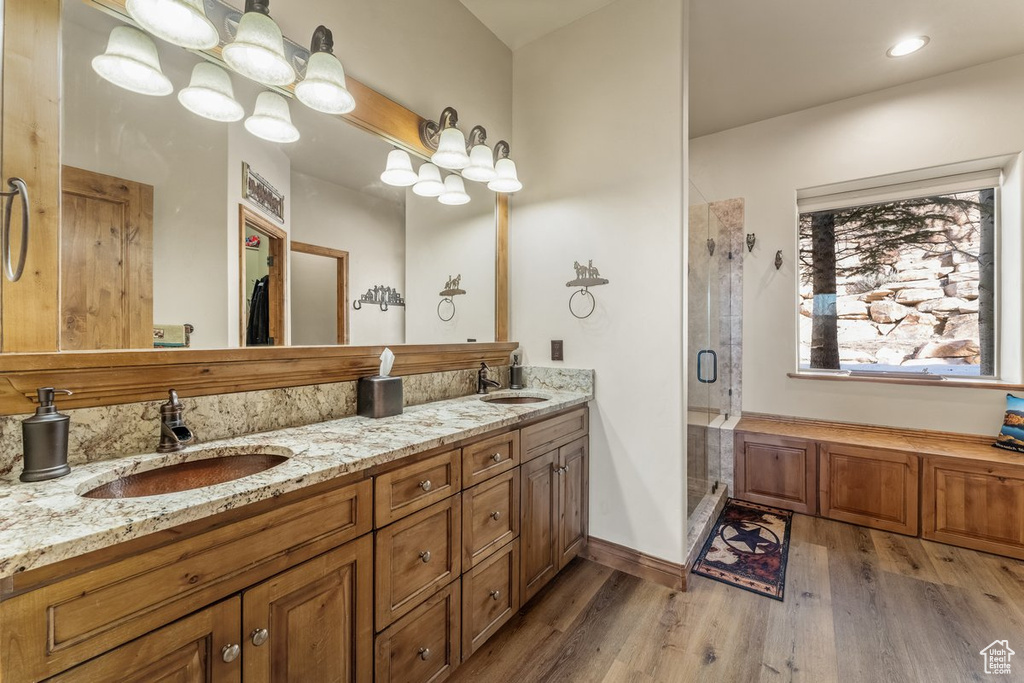 Bathroom with dual vanity, hardwood / wood-style floors, and an enclosed shower