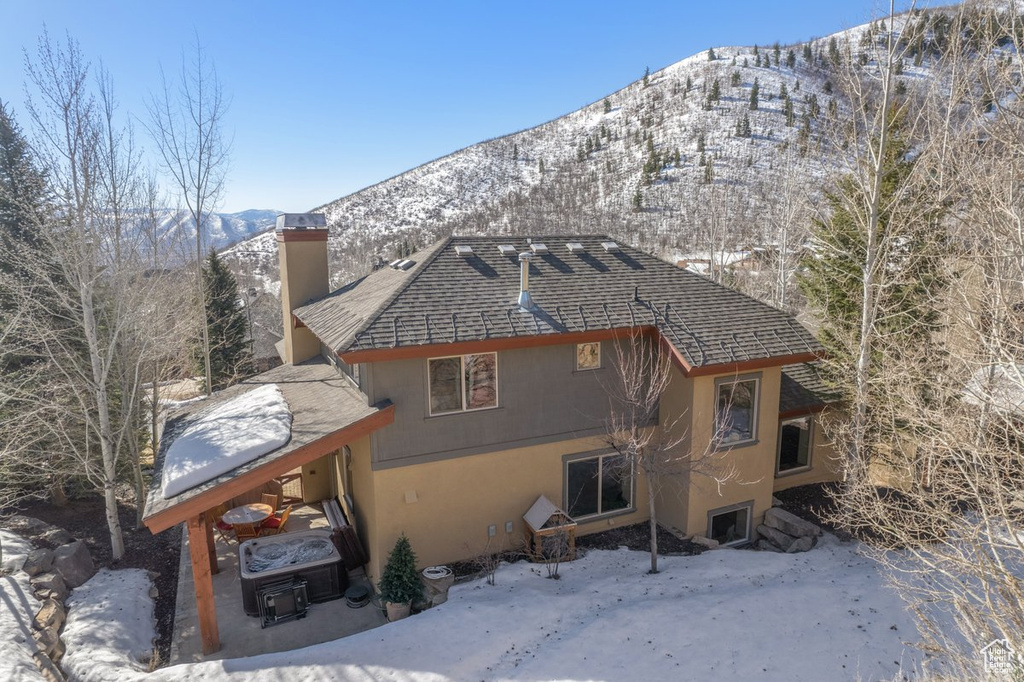 Snow covered rear of property featuring a mountain view