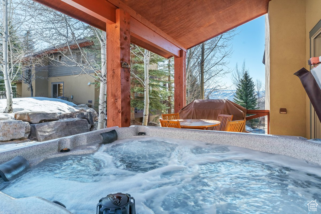 Snow covered pool featuring a hot tub