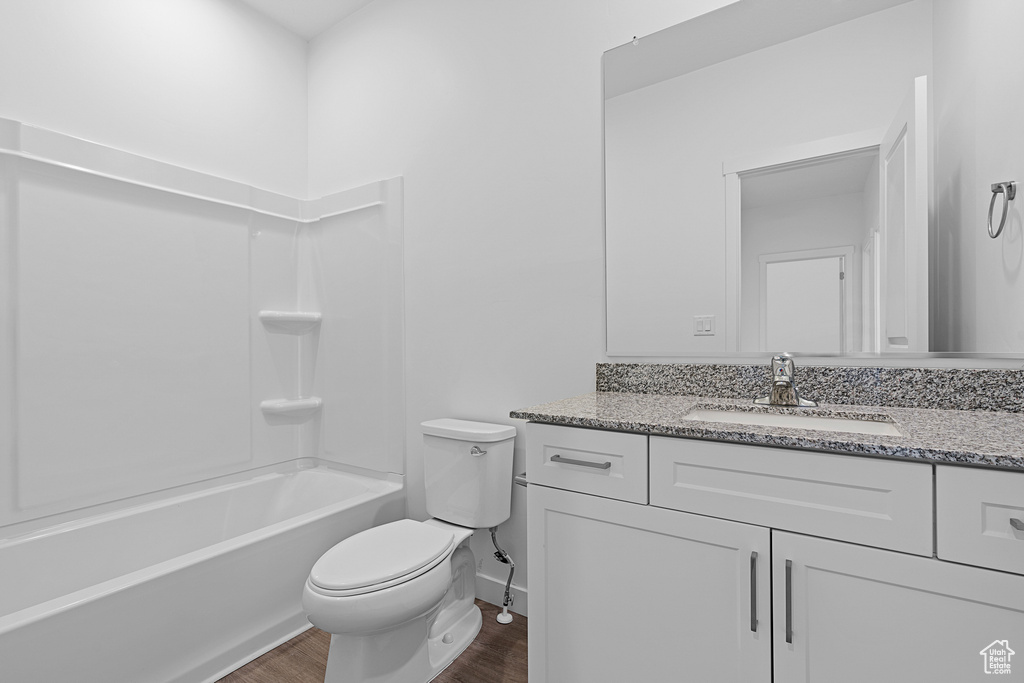 Full bathroom featuring toilet, hardwood / wood-style floors, large vanity, and bathtub / shower combination