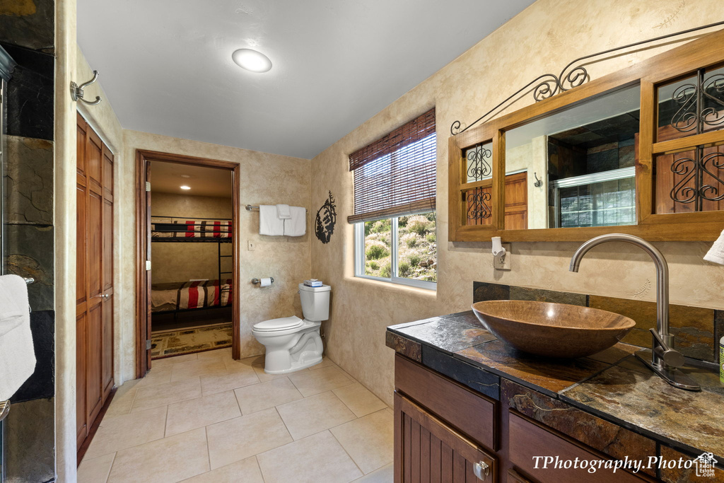 Bathroom with tile walls, tile floors, toilet, oversized vanity, and tasteful backsplash