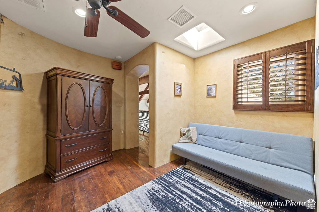 Interior space featuring ceiling fan, a skylight, and dark hardwood / wood-style floors