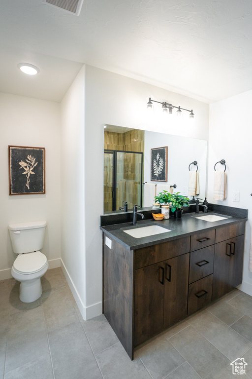 Bathroom with dual bowl vanity, tile flooring, and toilet