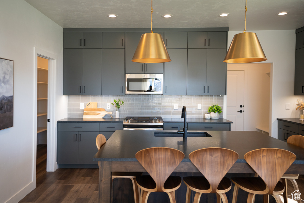 Kitchen with backsplash, sink, gray cabinets, and pendant lighting