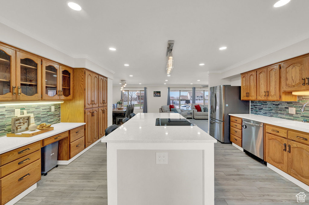Kitchen with light hardwood / wood-style flooring, dishwasher, a kitchen island, and backsplash