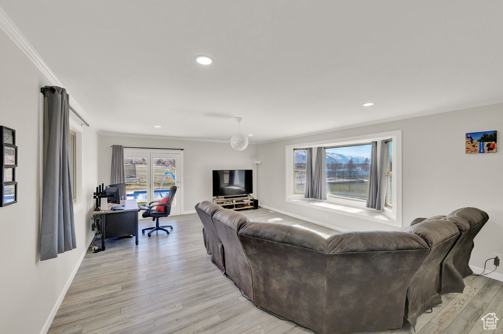 Living room featuring ornamental molding and light hardwood / wood-style flooring