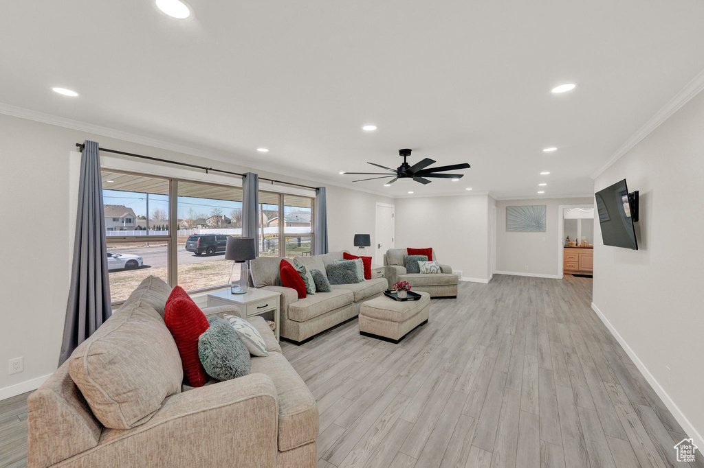 Living room featuring light hardwood / wood-style flooring, crown molding, and ceiling fan