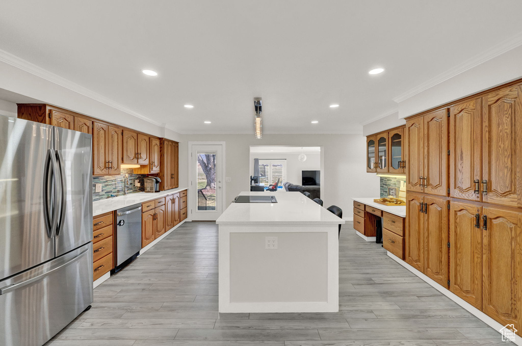 Kitchen with light hardwood / wood-style flooring, tasteful backsplash, appliances with stainless steel finishes, and a center island