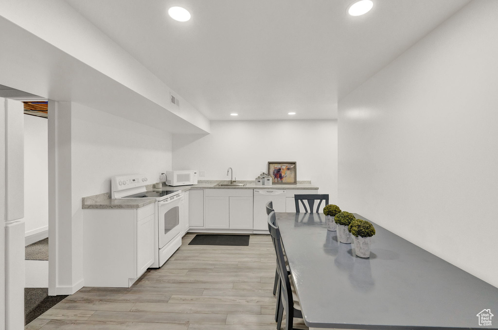 Kitchen featuring white cabinets, sink, white appliances, and light hardwood / wood-style flooring