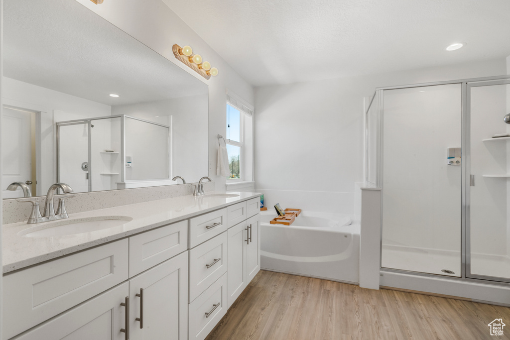 Bathroom with hardwood / wood-style flooring, double sink, oversized vanity, and separate shower and tub