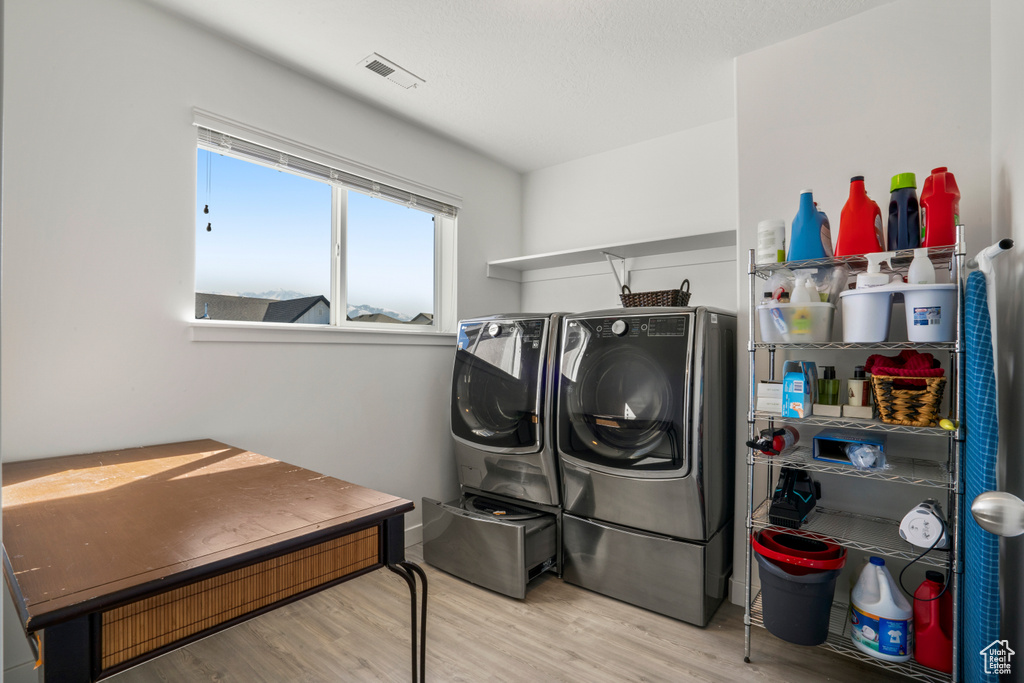 Laundry room with light hardwood / wood-style flooring and washer and clothes dryer