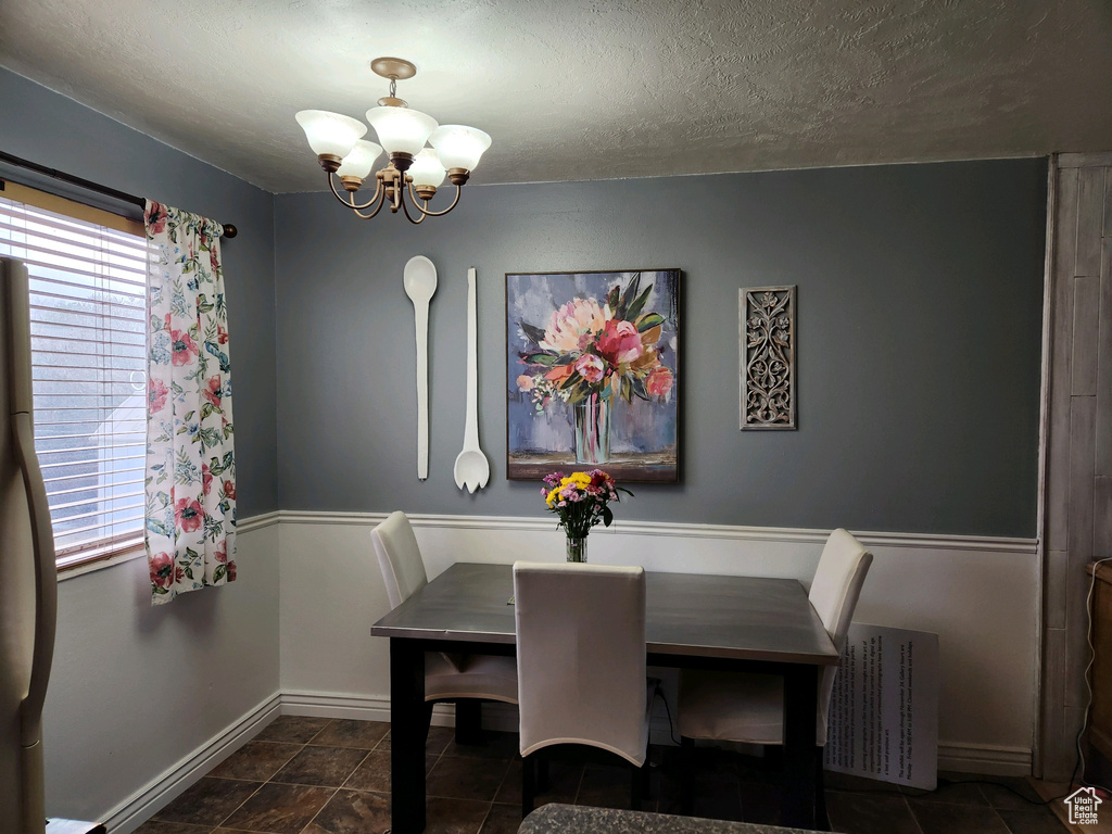 Dining area with a textured ceiling, an inviting chandelier, dark tile floors, and radiator