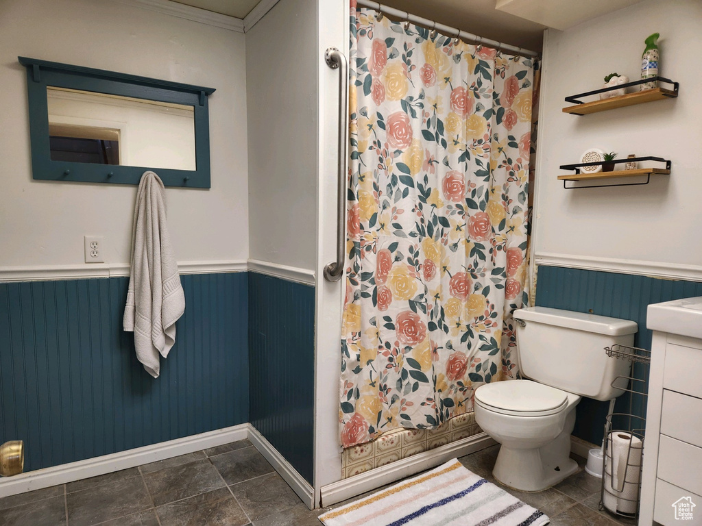 Bathroom with ornamental molding, tile flooring, vanity, and toilet