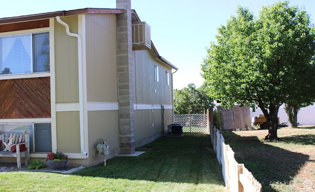View of side of home featuring central air condition unit and a lawn