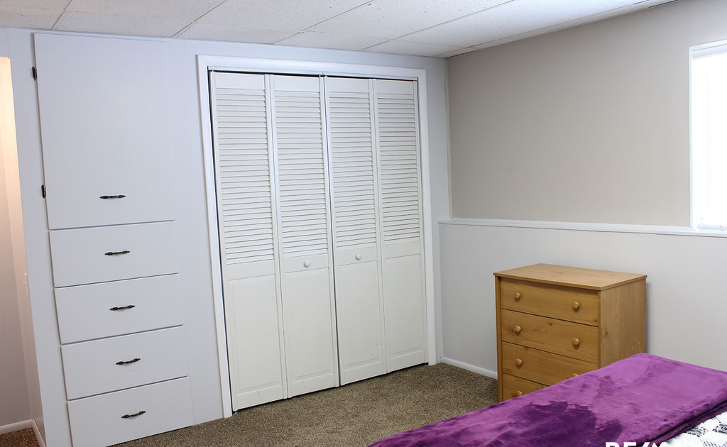 Carpeted bedroom with a closet and a paneled ceiling