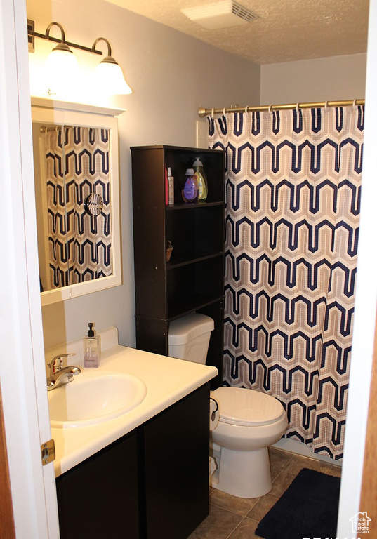 Bathroom featuring tile floors, a textured ceiling, toilet, and vanity