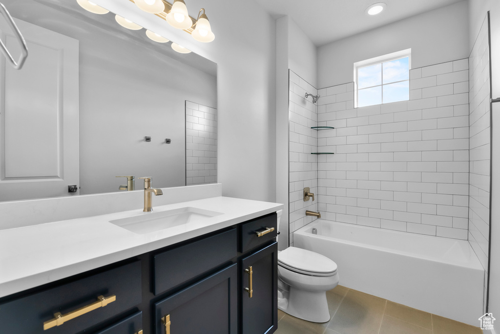 Full bathroom featuring tile floors, toilet, vanity, and tiled shower / bath