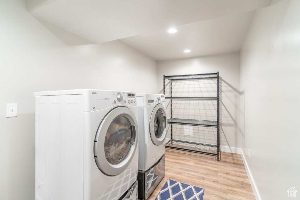 Washroom with light wood-type flooring and washer and clothes dryer