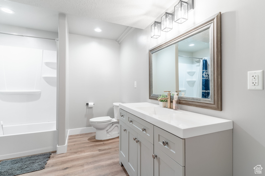 Full bathroom featuring vanity, a textured ceiling, toilet, hardwood / wood-style flooring, and shower / bath combo