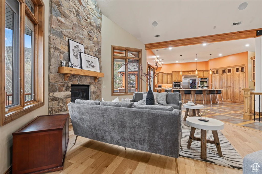 Living room featuring a stone fireplace, light hardwood / wood-style floors, and high vaulted ceiling