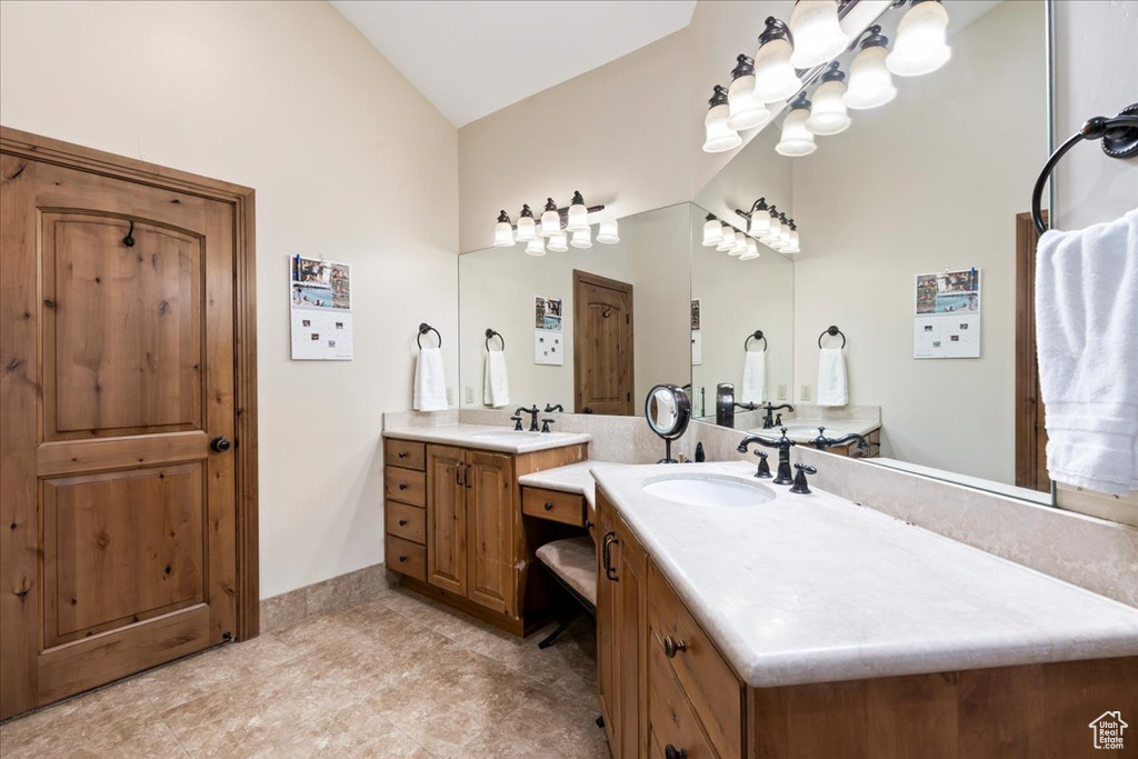 Bathroom with lofted ceiling, tile flooring, and double vanity