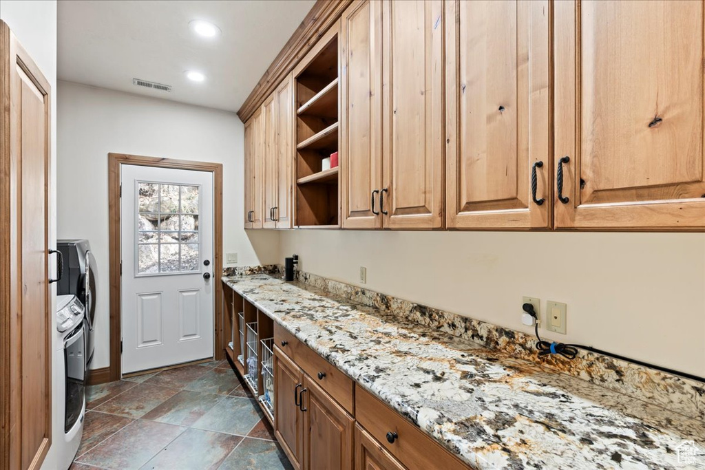 Kitchen with light stone counters, washer / dryer, and dark tile flooring