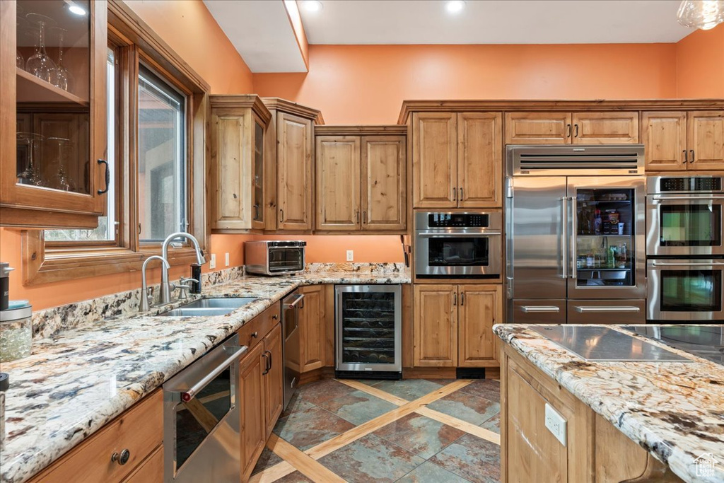 Kitchen featuring light tile floors, sink, stainless steel appliances, and beverage cooler