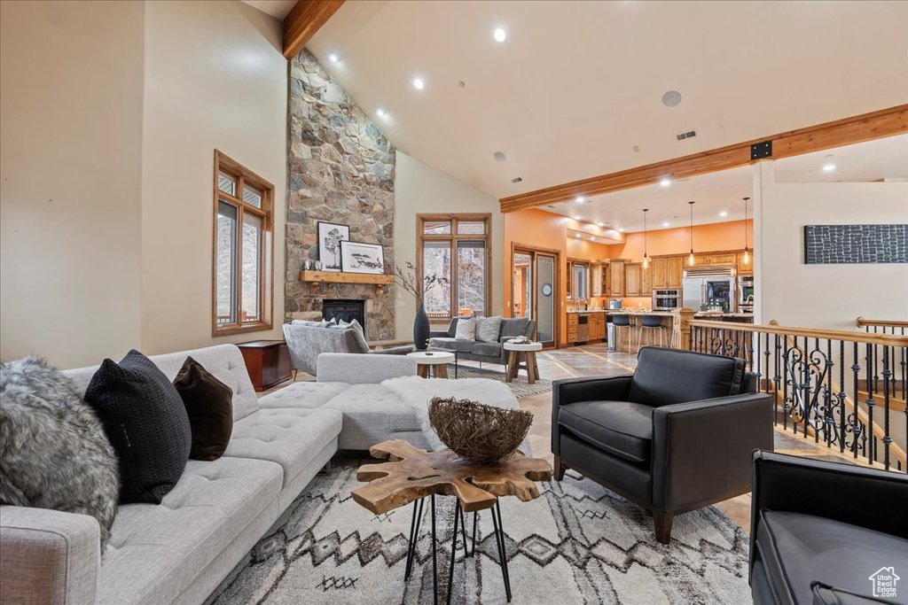 Living room featuring high vaulted ceiling, a stone fireplace, and beam ceiling