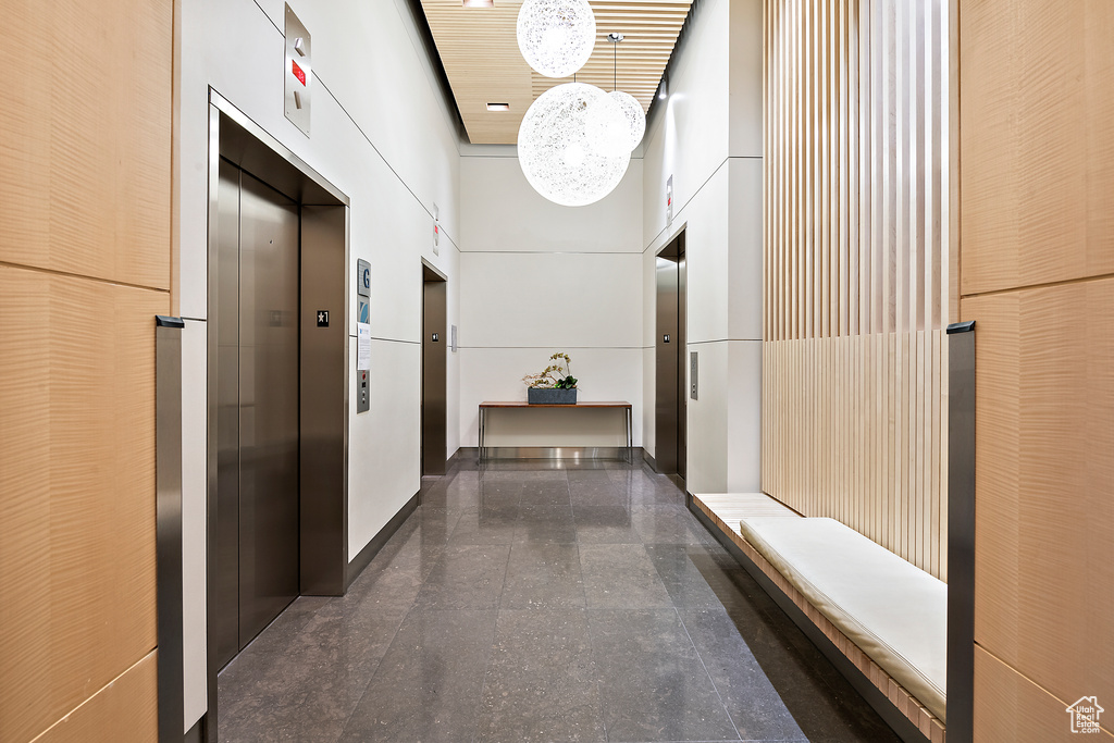 Hall featuring elevator, a towering ceiling, and dark tile flooring