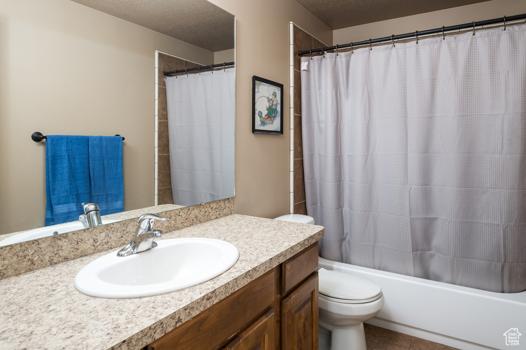 Full bathroom featuring vanity, shower / bath combo, a textured ceiling, tile floors, and toilet