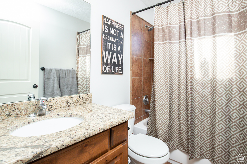Full bathroom with shower / tub combo with curtain, toilet, and vanity with extensive cabinet space