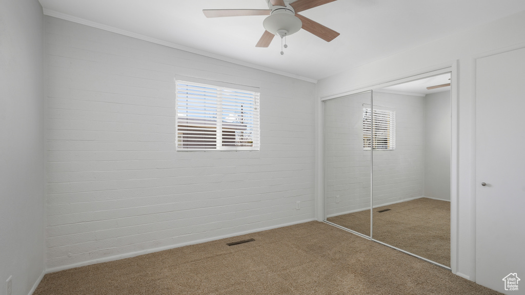 Unfurnished bedroom featuring a closet, crown molding, light carpet, and ceiling fan
