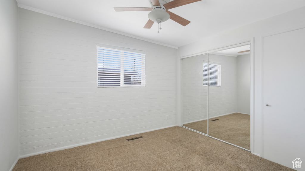 Unfurnished bedroom with a closet, ceiling fan, ornamental molding, and light colored carpet