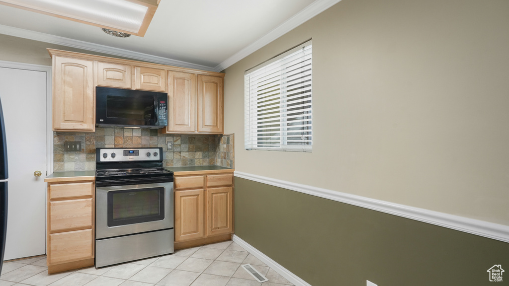 Kitchen with electric stove, tasteful backsplash, light brown cabinetry, and light tile floors
