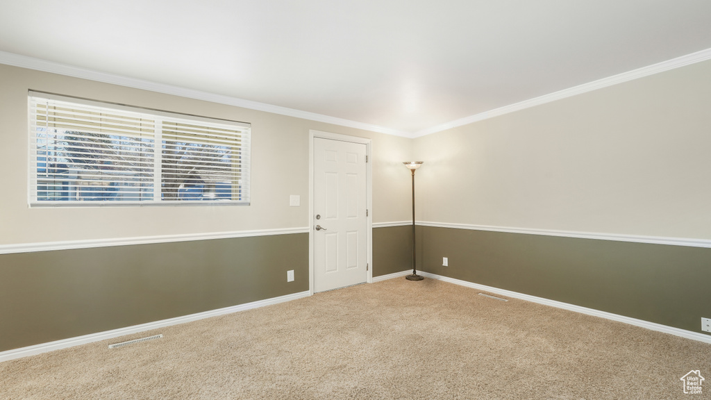 Empty room featuring ornamental molding and light carpet
