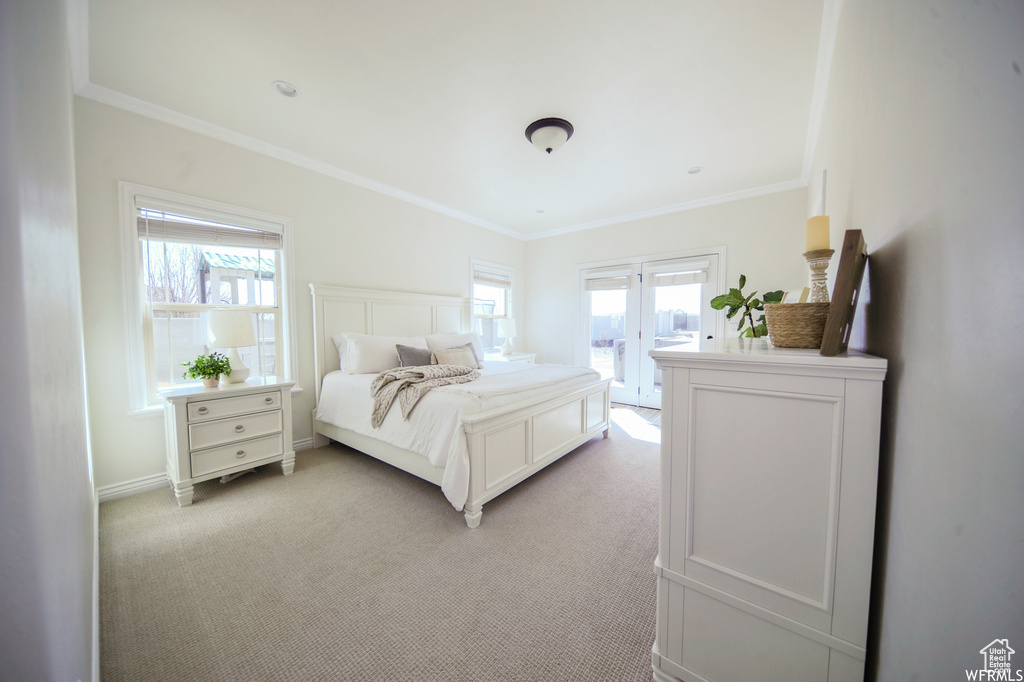 Bedroom with crown molding, light carpet, french doors, and access to outside