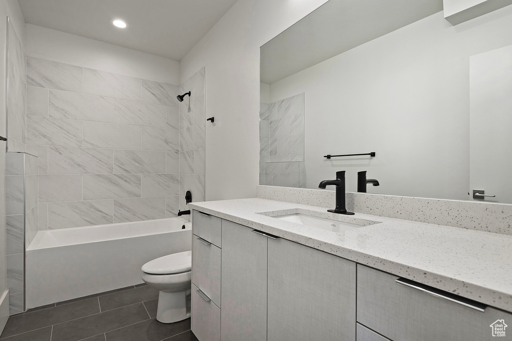 Full bathroom with toilet, tiled shower / bath combo, tile floors, and oversized vanity