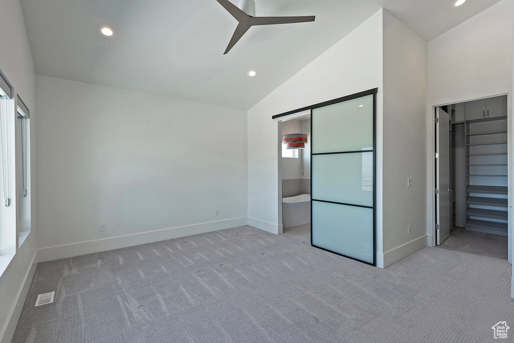 Unfurnished bedroom featuring ensuite bath, ceiling fan, high vaulted ceiling, and light colored carpet