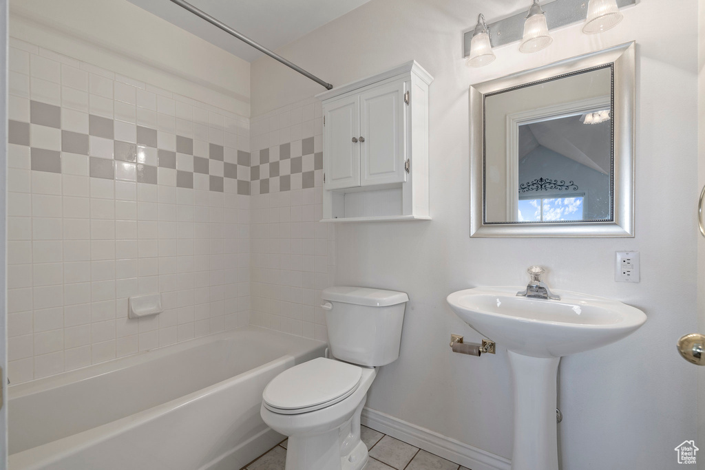 Bathroom featuring tile floors, tiled shower / bath, and toilet