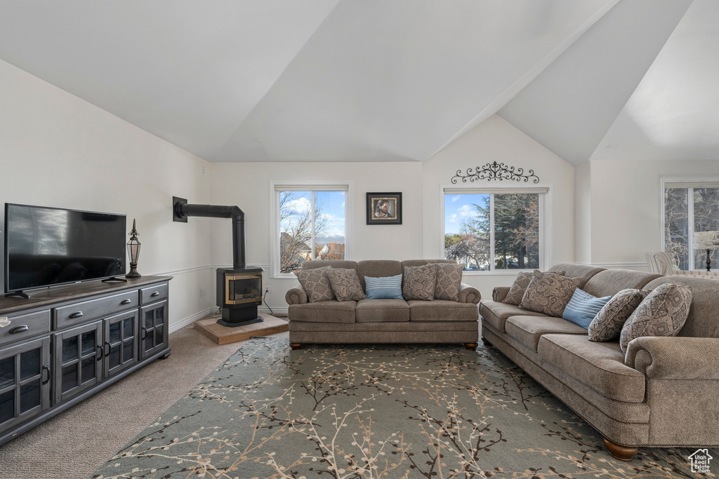 Carpeted living room featuring lofted ceiling and a wood stove