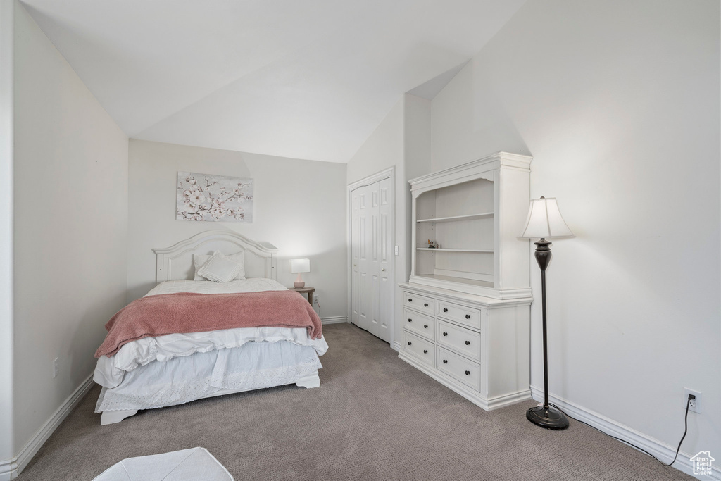 Carpeted bedroom featuring a closet and vaulted ceiling