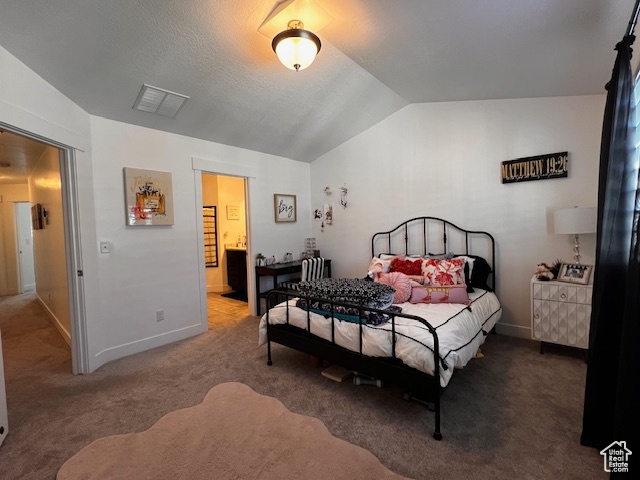 Bedroom featuring vaulted ceiling, carpet flooring, and connected bathroom