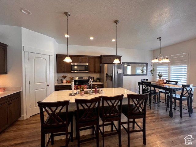 Kitchen featuring hanging light fixtures, stainless steel appliances, a chandelier, and dark hardwood / wood-style flooring