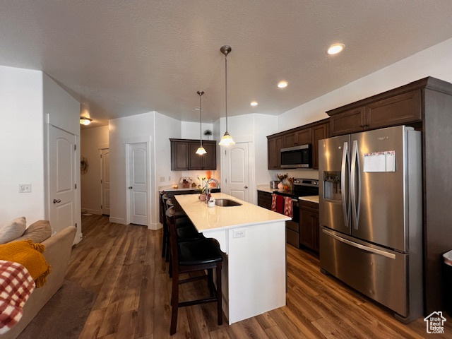Kitchen with a center island with sink, stainless steel appliances, dark hardwood / wood-style floors, a breakfast bar area, and sink