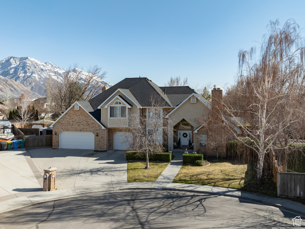 Front facade with a mountain view, a front yard, and a garage